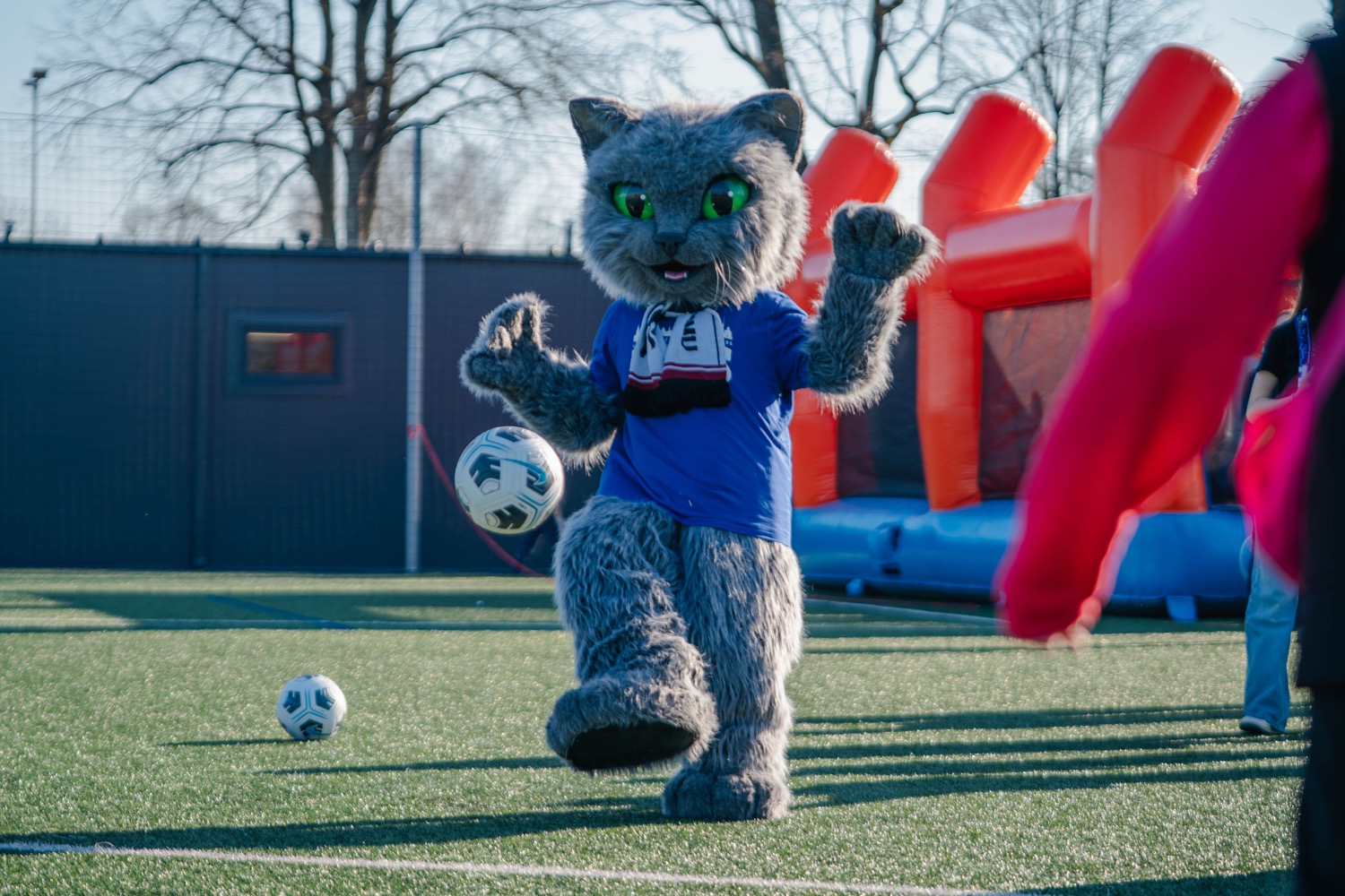 Kluba maskotka spēlē futbolu ar bērniem